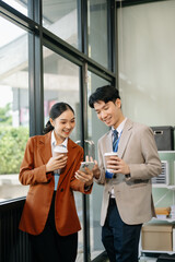 Happy two Asian business holding coffee cup in modern office.