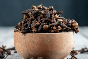 close shot of a wooden bowl filled cloves with blurry background