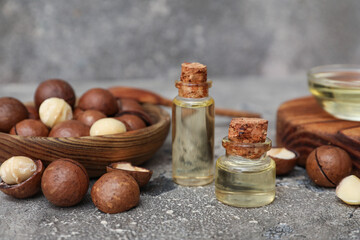 Bottles of oil with macadamia nuts on grunge background, closeup