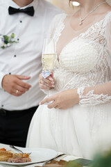 The newlyweds are holding glasses of champagne while standing near the festive table.
