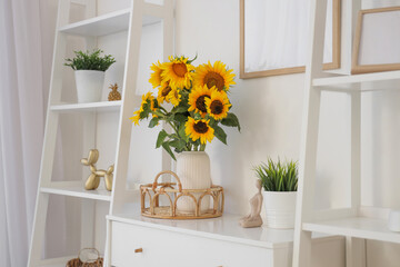 Vase with sunflowers and plant on commode in light living room