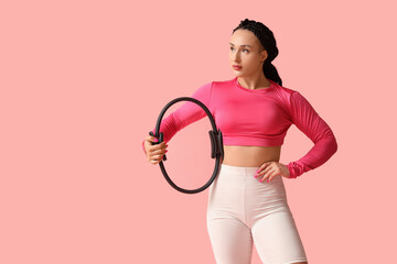 Female bodybuilder with pilates circle on pink background