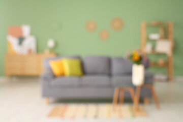 Soft sofa and wild flowers on coffee table in living room. Blurred view