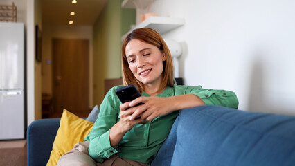 Obraz premium Woman relaxing on the couch and using smartphone