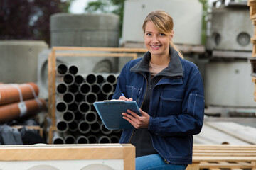 female worker with clipboard in building materials yard