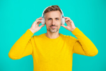 Modern lifestyle. Man listening audio in music headphones. Caucasian man isolated on blue. Mature...