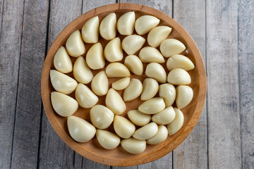 top view of a wooden plate of garlic on wooden table