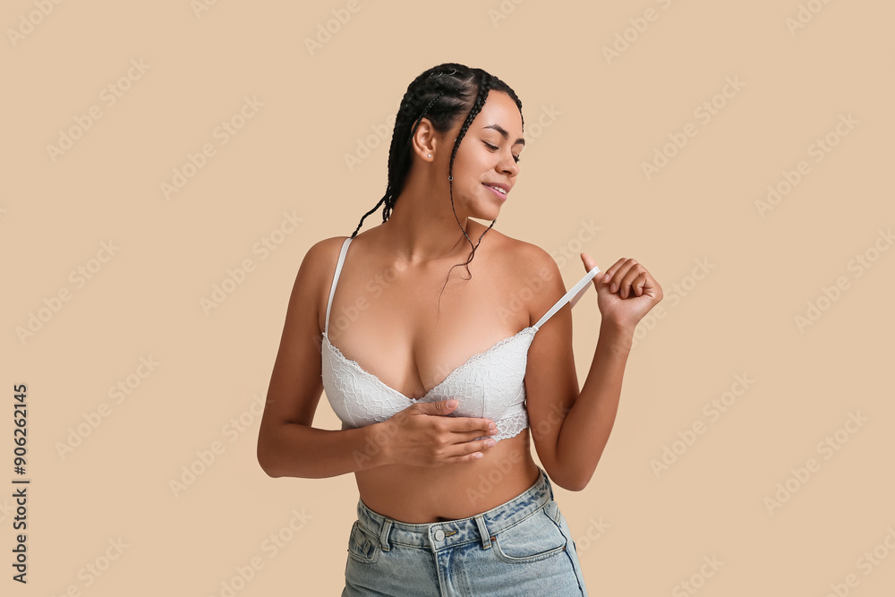 Wall mural young african-american woman in bra on beige background