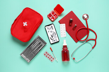 Mobile phone with first aid kit and medical supplies on green background. Telemedicine concept