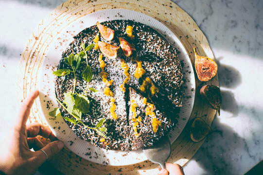 Healthy Kitchen - woman cuts vegan chocolate cake with fresh figs