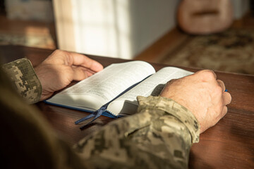 Hands of soldier in uniform holding the Holy Bible. Natural aesthetic light