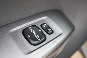 Modern hybrid electric car closeup interior detail. Driver door control panel in armrest buttons of mirror control.