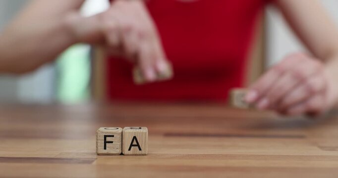 Woman replaces wooden blocks spelling Fake with word Fact. Journalist highlights importance of verifying information to ensure truth slow motion