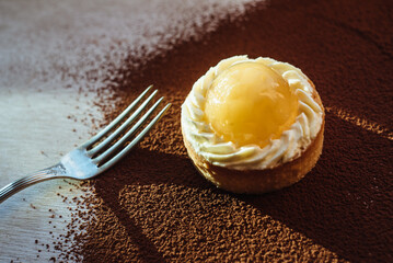 Lemon tartlet on a dark background. Fashionable European dessert with fruit filling.