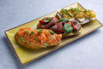 different types of bruschetta. With salmon, meat, soft cheese, herbs