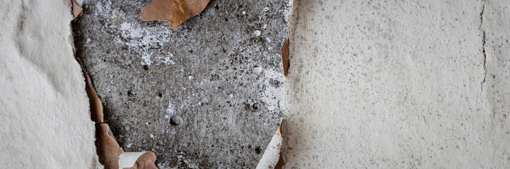 Torn old faded paper wallpaper on a concrete wall. Ragged scraps of white paper on a gray background. Vintage texture for background and design. Closeup view with copy space for text.