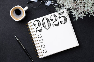 New year resolutions 2025 on desk. 2025 goals list with notebook, coffee cup, plant on black table....