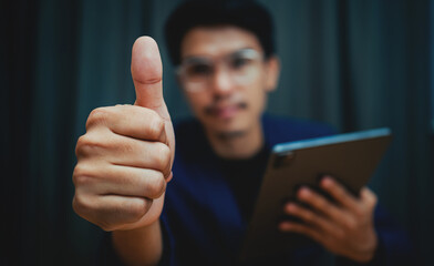 A man is giving a thumbs up while holding a tablet. Concept of approval and satisfaction