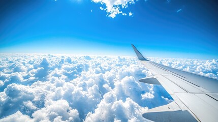 Airplane wing and clear blue sky with fluffy cumulus clouds in a panoramic view, providing ample space for travel-related content.