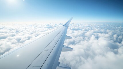 Obraz premium Close-up of an airplane wing against a clear blue sky and fluffy clouds, providing a panoramic view perfect for flight and travel imagery.