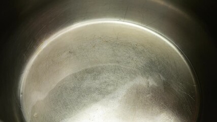 Popcorn grains fall to the bottom of a metal pan with hot vegetable oil. The process of cooking popcorn. Slow motion. - Powered by Adobe