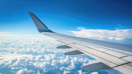 Obraz premium Close-up of an airplane wing with a clear blue sky and fluffy clouds in the background, offering a panoramic view ideal for travel ads.