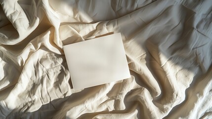 Blank paper card sheets with copy space on wrinkled bed blanket cloth with aesthetic warm sunlight shadows Flat lay top view