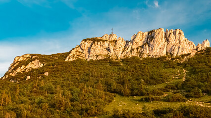 Alpine summer evening view with a summit cross at Mount Kampenwand, Aschau, Chiemgau, Rosenheim, Bavaria, Germany
