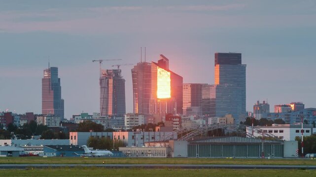 Day to evening transition time-lapse shot of Warzaw city downtown with high-rise modern glass skyscrapers and buildings on horizon. View from Chopin international airport, summer day cityscape