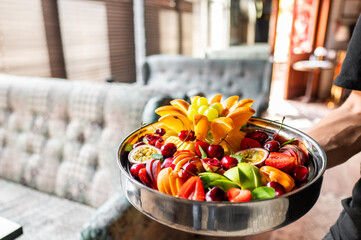 A vibrant bowl of fresh fruits including sliced kiwis, oranges, and cherries, presented in a stylish interior setting. Perfect for healthy eating, food blogs, and lifestyle imagery.
