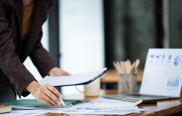 Asian business woman hand writing note on paperwork at desk.