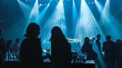 Guests enjoy a sophisticated evening under blue lights, engaging in conversations and savoring their drinks at an elegant event.