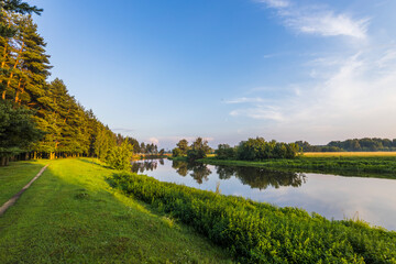 A beautiful river with a green bank and trees in the background