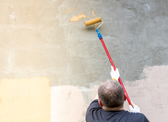 A man is painting a wall with a roller