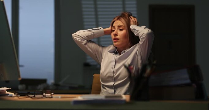 Scared woman office worker squeezes head passing deadline at workplace. Female manager panics losing financial data at stormy night