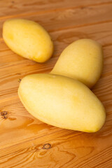 Delicious ripe juicy mangos on wooden table, top view