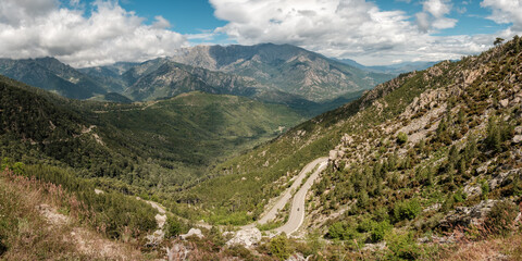A motorcycle passes along the winding D69 road though the forests and  mountains of the interior of the Mediterranean island of  Corsica near Bocca di Sorba