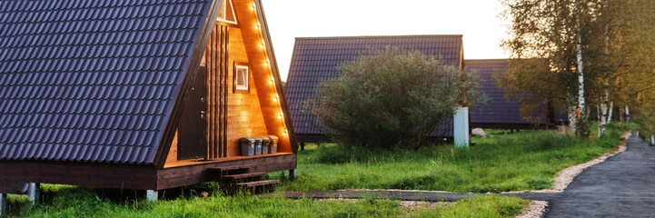 The concept of glamping and renting a chalet for weekend. Wooden house with a veranda in nature around coniferous trees