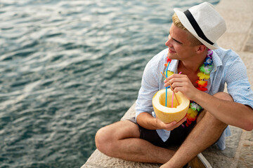 Portrait of a handsome young man enjoying refreshing drink on the beach