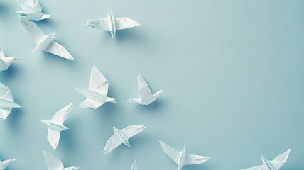 Flock of white origami paper birds on a light blue background