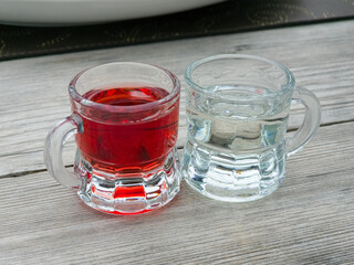 Close-up shot of two small glasses containing alcoholic drinks on a rustic table