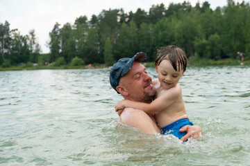 Summer outdoor activities. Dad and small child having fun swimming in lake.