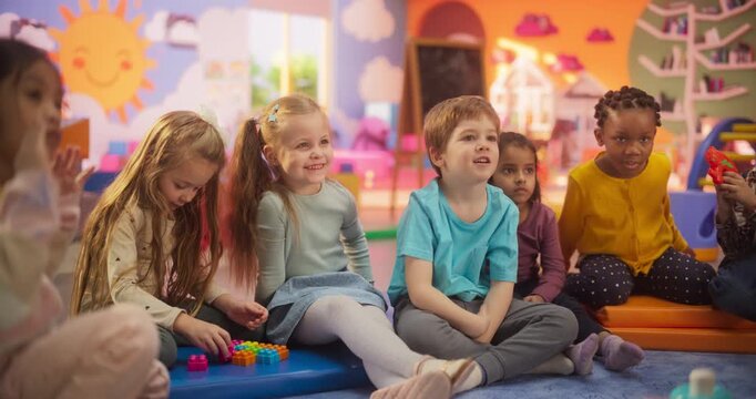 Happy Kindergarten Pedagogue Having a Conversation with Kids, Using Enthusiastic Teaching Methods in a Modern Colorful Kindergarten. Female Educator Stimulating Linguistic and Social Skills