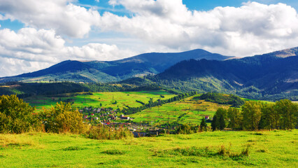 Obraz premium mountainous countryside landscape of ukraine. view in to the distant rural valley from meadow. trees on the hills of carpathian borzhava ridge. sunny weather, clouds on the sky. volovets district