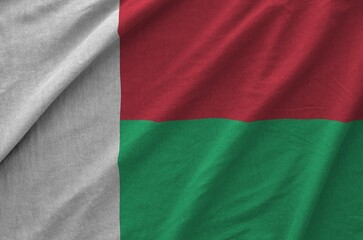 Madagascar flag depicted on folded wavy fabric of old cloth close up