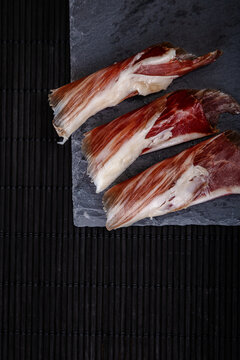 Slices of serrano ham on dark textured background