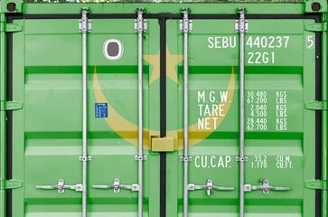 Mauritania flag depicted on metal doors of shipping cargo container outdoors in docks area close up