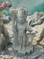 Indian Stone Carving Artists Creating Hindu God Statue Of Stone. Cutting rock with grinder. Stone sculptor creates sculpture on workshop. Young artisan at work sculpture.