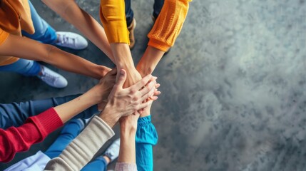 A group of people are holding hands in a circle. The people are wearing different colored shirts and shoes. Scene is one of unity and togetherness