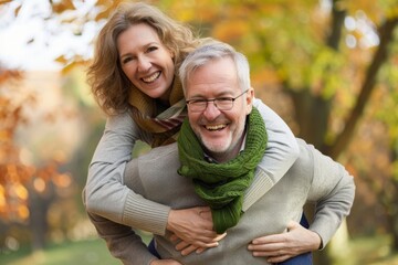 Fototapeta premium Happy couple enjoying a piggyback ride in a bright autumn park.